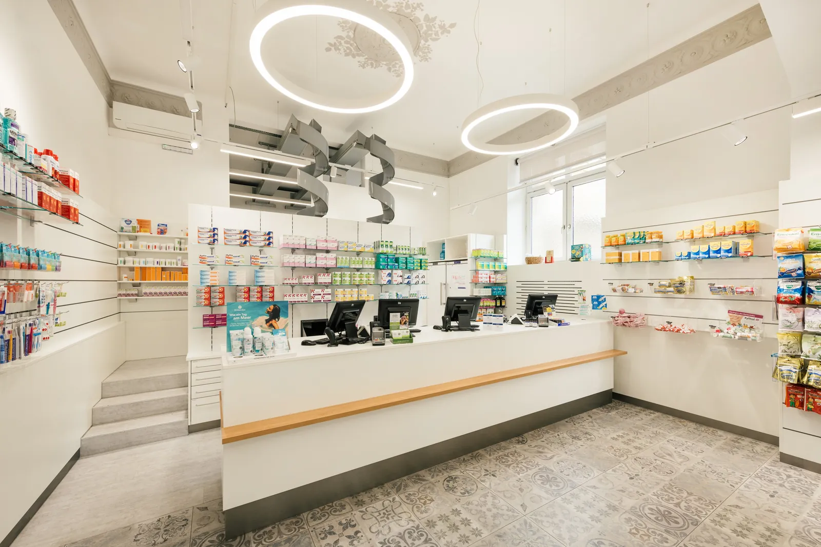 Weiße Theke mit Kassenplätzen im Verkaufsraum der Saggen-Apotheke